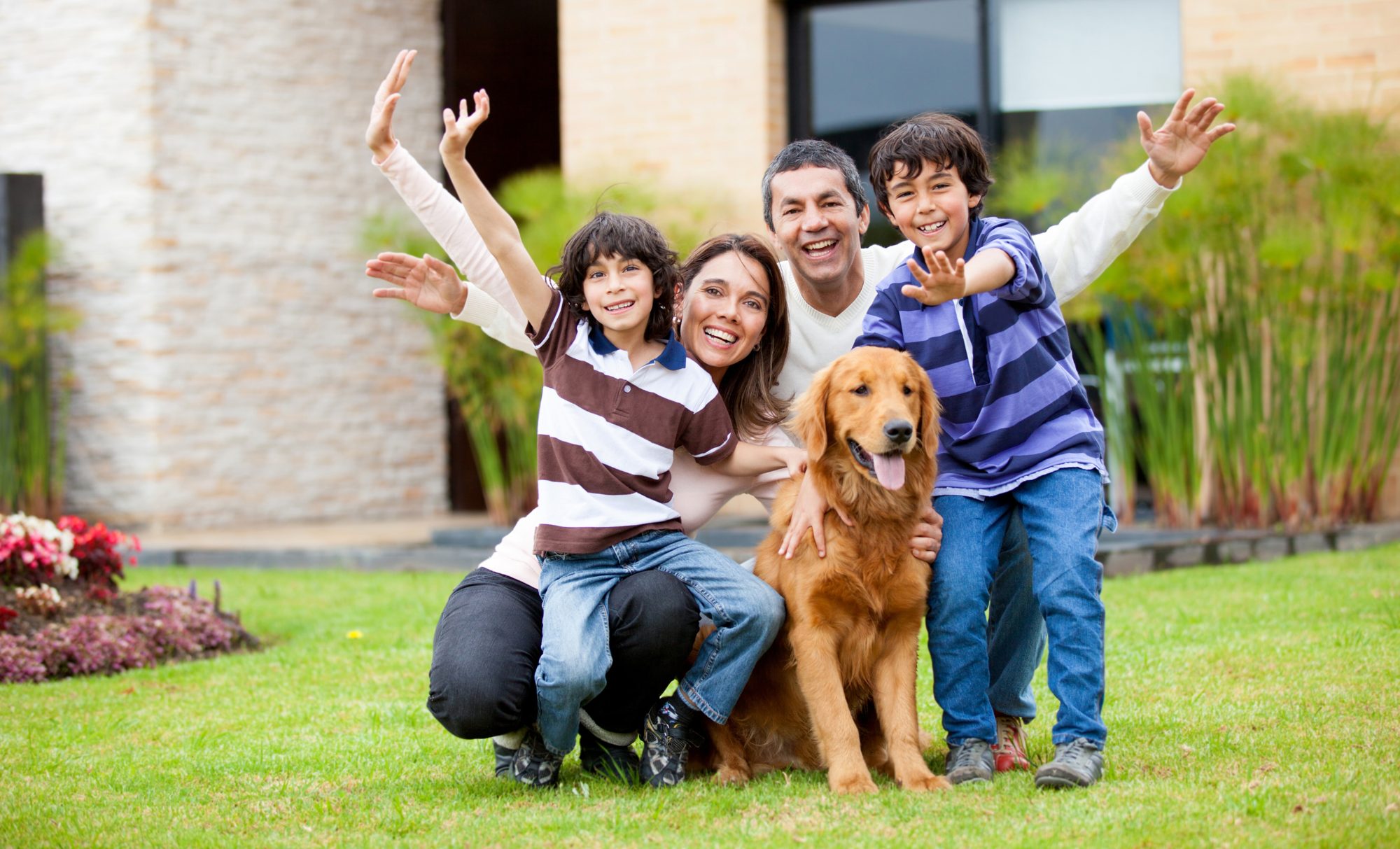 A happy family with their dog outside their new home